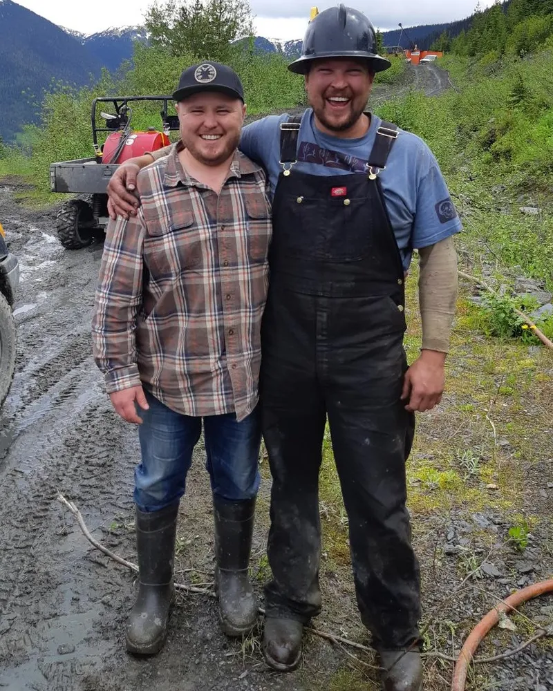 Two crew members smiling on a muddy access road